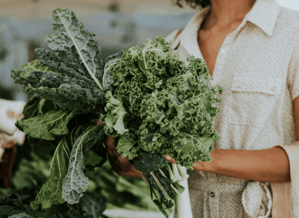 Featured-Image-Blog a women shopping holding a bundle of leafy greens in her hand
